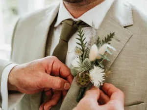 Close up of Groom having his natural buttonhole placed on his lapel | Insert Wedding Flowers |