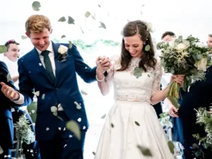 Bride and Groom walk down the aisle whilst showered with foliage confetti, bride holding her white and green bouquet | Insert Wedding Flowers | Photo Credit: Karen Flowers
